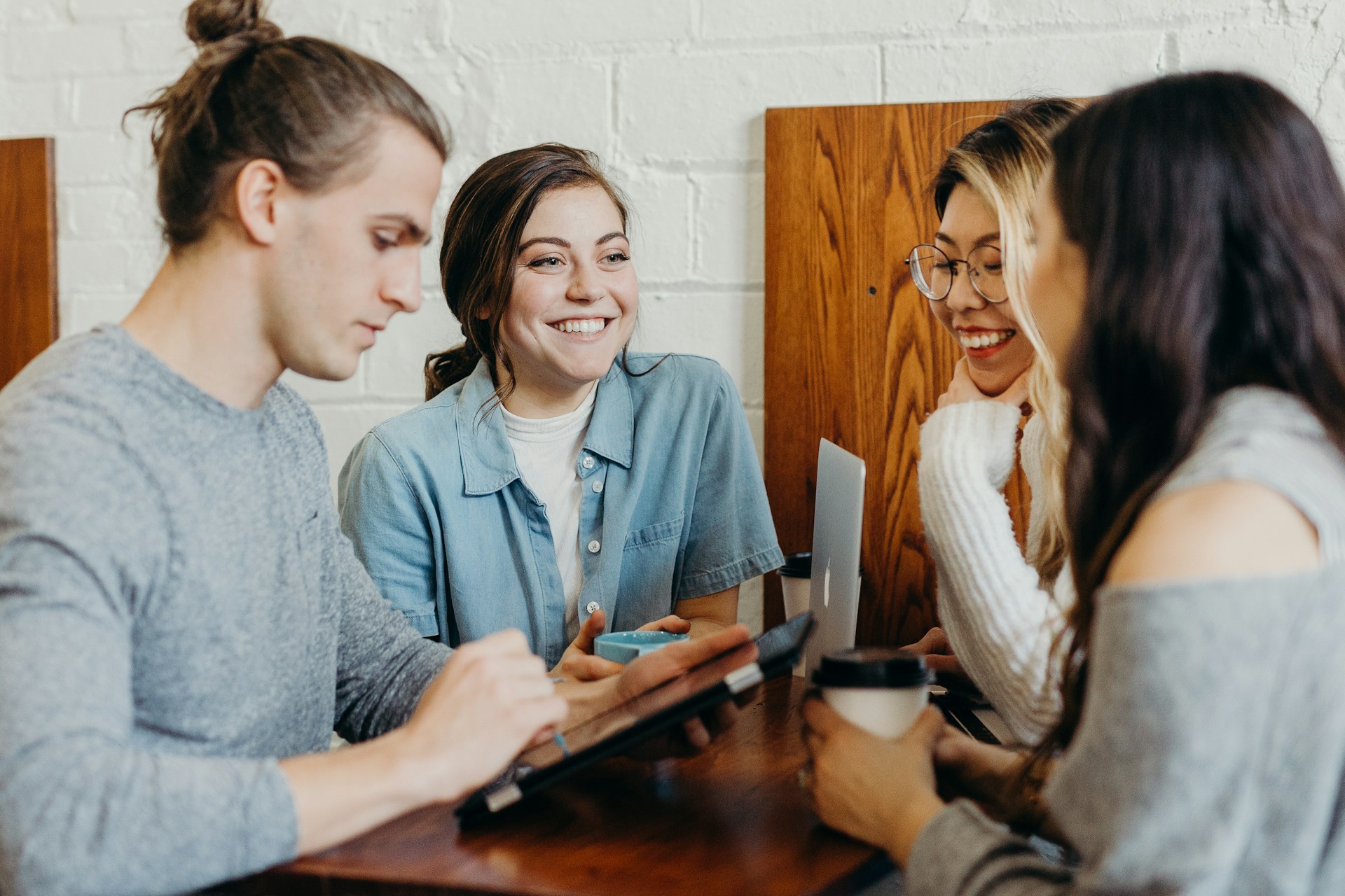 Four colleagues gathered around a tablet at a shared table