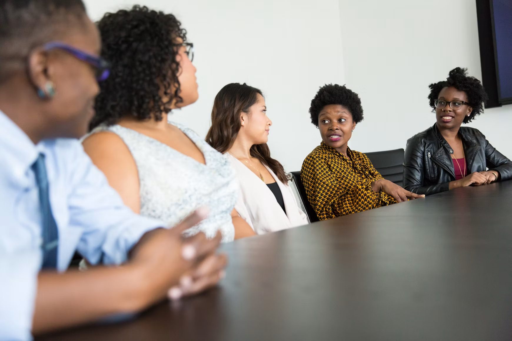 Colleagues in discussion around a conference table, one speaking