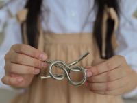 A girl holding a loose metal knot