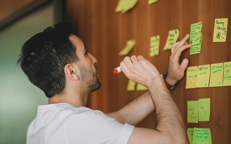A facilitator adding sticky notes to a wall of ideas during a working session