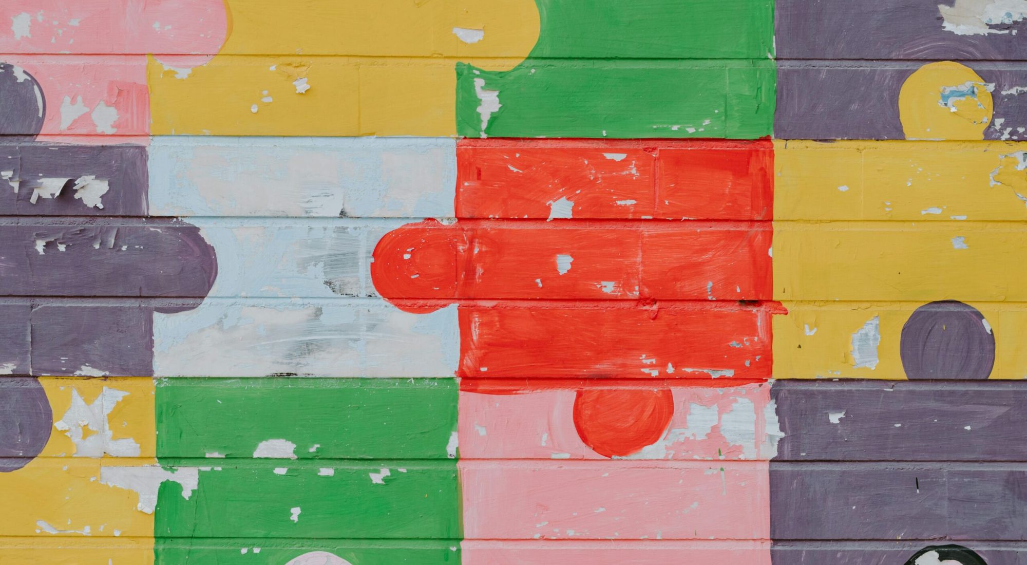 A wood panel wall painted to look like colorful interlocking puzzle pieces